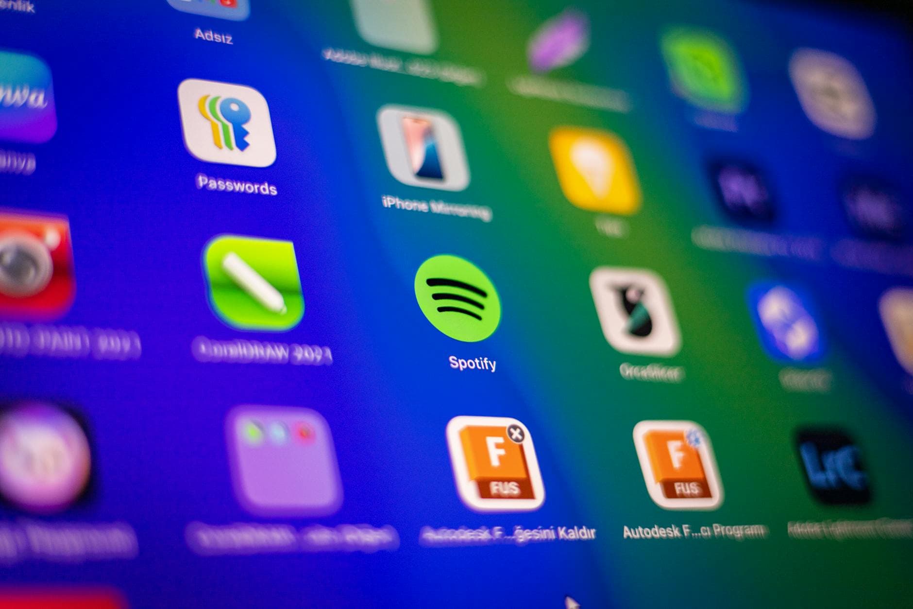 Ein Bildschirm zeigt bunte App-Symbole wie Spotify, Passwords, CorelDRAW 2023 und iPhone Mirroring.