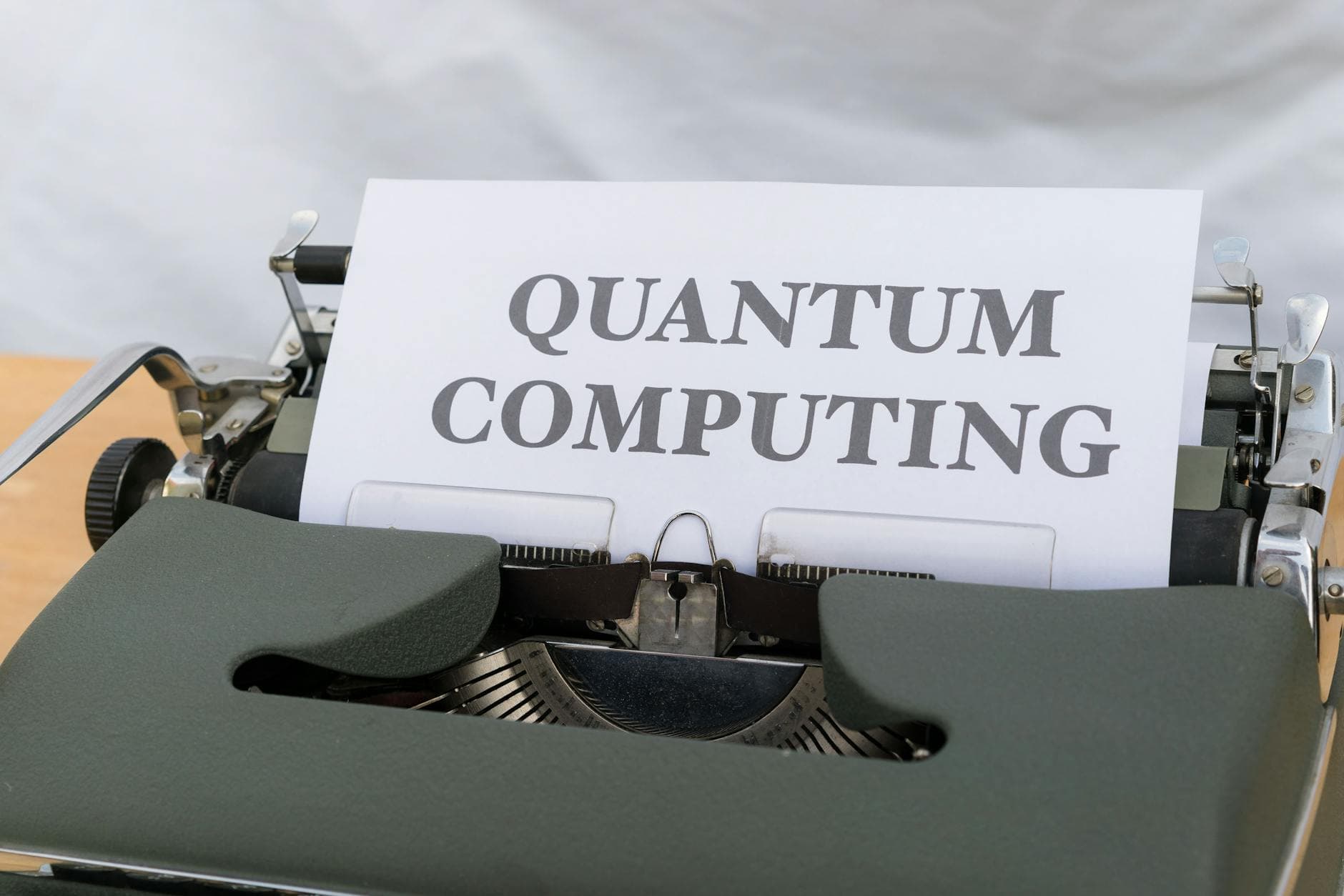 Alte Schreibmaschine mit einem Blatt Papier, auf dem in Großbuchstaben "QUANTUM COMPUTING" steht.