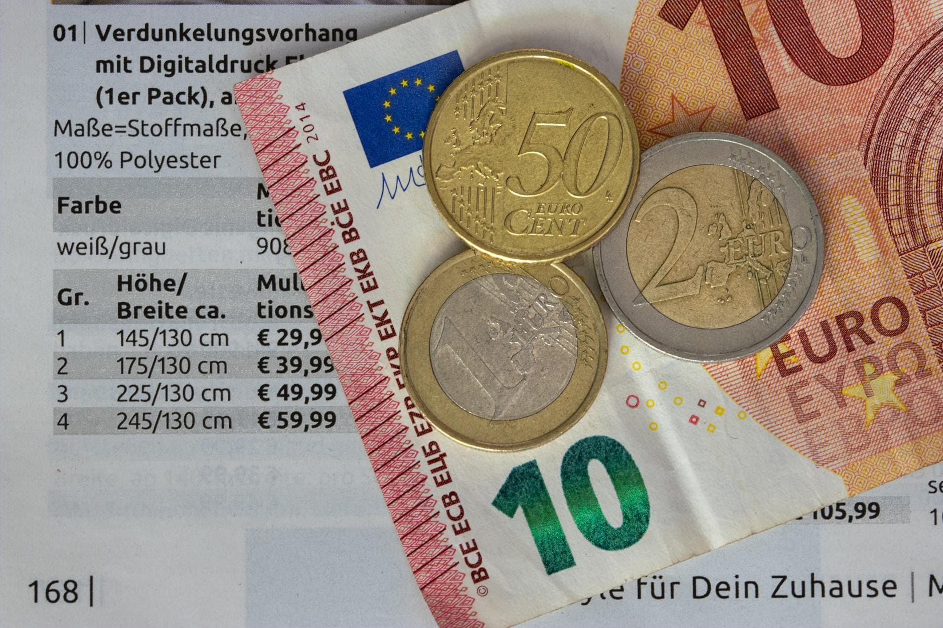 Ein Zehn-Euro-Schein, eine 50-Cent-, eine 1-Euro- und eine 2-Euro-Münze liegen auf einem deutschen Katalog mit Preisliste.
